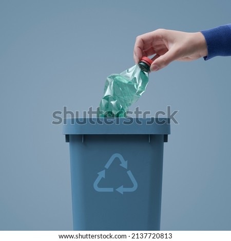 Woman putting a plastic bottle in a trash bin, waste sorting and recycling concept