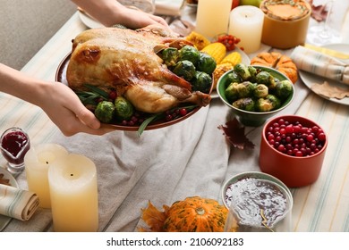 Woman Putting Plate With Delicious Roasted Turkey On Served Table