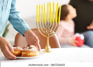 Woman Putting Plate With Tasty Donuts For Hannukah On Table, Closeup