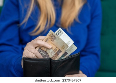 Woman putting Polish money into her wallet - Shutterstock ID 2370467809