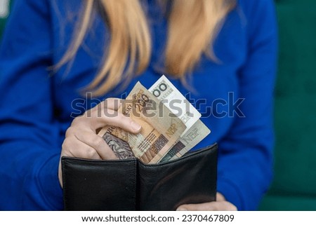 Woman putting Polish money into her wallet