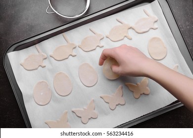 Woman putting raw Easter cookies on baking tray, closeup