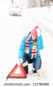 Woman putting reflector triangle car breakdown winter snow sign