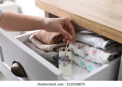 Woman Putting Scented Wax Sachet Into Dresser Drawer With Folded Clothes At Home, Closeup