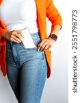 Woman putting smartphone with blank screen in jeans pocket