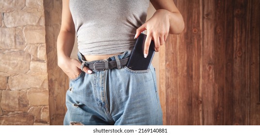 Woman Putting Smartphone In Pocket Of Jeans.