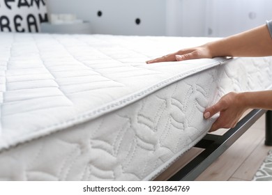 Woman putting soft orthopedic mattress on bed