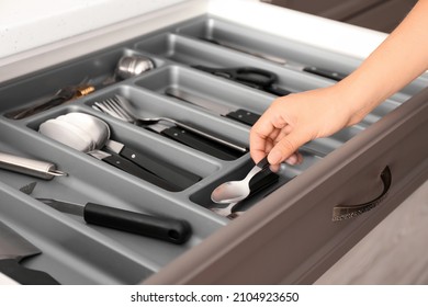 Woman Putting Spoon Into Kitchen Drawer, Closeup