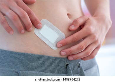 Woman putting sticking plaster on skin scar after abdomen surgery. 