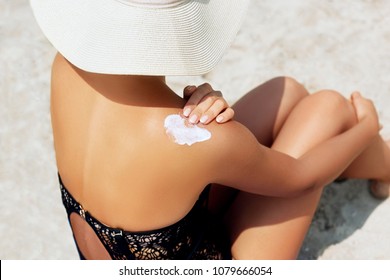 Woman Putting Sunblock Lotion On Shoulder Before Tanning During Summer Holiday On Beach Vacation Resort 