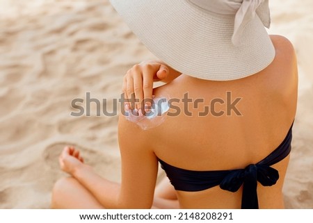 Woman putting sunblock lotion on shoulder before tanning during summer holiday on beach. Sun cream. Suntan.  Beautiful Woman Applying  Sunscreen Solar Cream. Skin care. Sun protection