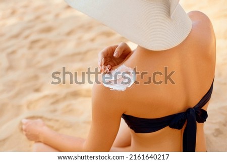 Woman putting sunblock lotion on shoulder before tanning during summer holiday on beach vacation resort. Sun cream. Suntan.  Beautiful Woman Applying  Sunscreen Solar Cream. Skin care.