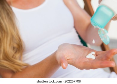 Woman Putting Sunblock On Her Hand At The Beach On A Sunny Day