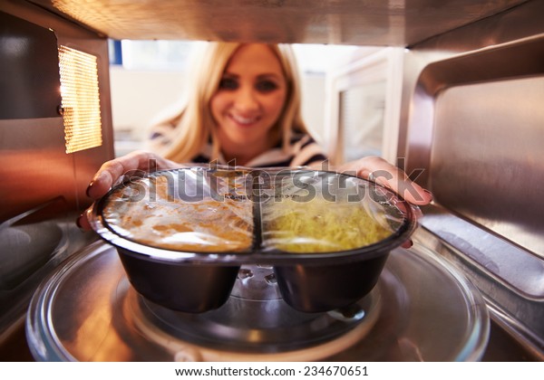 Woman\
Putting TV Dinner Into Microwave Oven To\
Cook