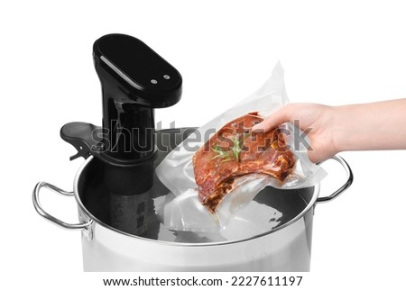 Woman putting vacuum packed meat in pot with sous vide cooker on white background, closeup