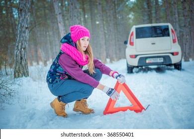 Woman putting warning triangle car breakdown winter snow sign