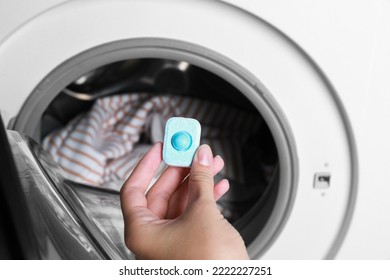 Woman putting water softener tablet into washing machine, closeup - Powered by Shutterstock