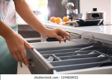 Woman putting whisk into kitchen drawer - Powered by Shutterstock