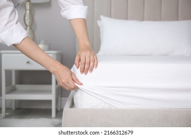 Woman putting white fitted sheet over mattress on bed indoors, closeup - Shutterstock ID 2166312679
