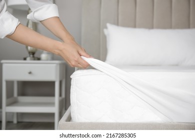 Woman Putting White Fitted Sheet Over Mattress On Bed Indoors, Closeup