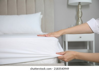 Woman putting white fitted sheet over mattress on bed indoors, closeup - Shutterstock ID 2183540949