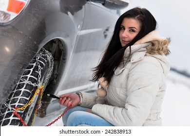 Woman Putting Winter Tire Chains On Car Wheel 