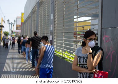 Woman Queuing For The Supermarket, Keeping Social Distance With Mask