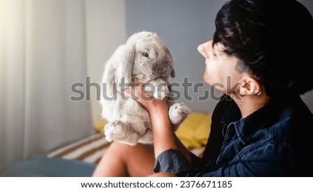 Woman with rabbit having tender moment at home - Owner and pet friendship relationship