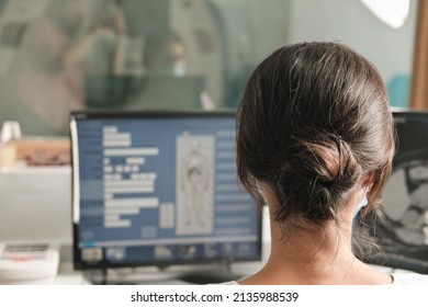 Woman Radiologist Looking At Monitor With An X-ray Image. Examining And Diagnostics Of A Trauma. Rear View Of Young Female X-ray Doctor.