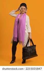 Woman In Raincoat With Big Black Shopping Bag On Yellow Background