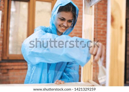a woman in a raincoat is painting wood in a village