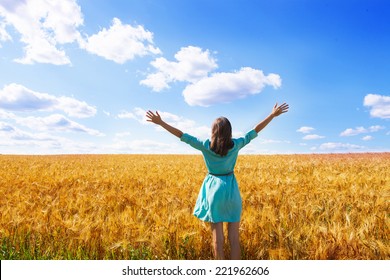 Woman raising arms enjoying sunlight in field