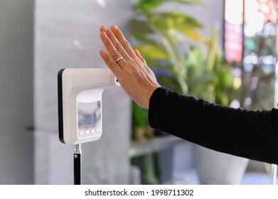 Woman Raising Hand At Check Infrared Temperature Measurement Screening Point For COVID-19 ​or Fever Before Entering Public Area, Body Temperature Screening With Her Palm