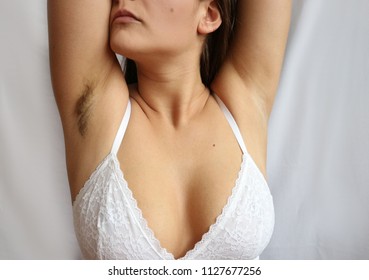 Woman raising her hands, one armpit shaved, the second is not, depilation and armpits care concept. Before and after shaving, hairy and clean armpit.