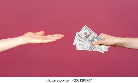 The Woman Reached A Hand To Take Money Isolated On A Pink Background. Palm Up