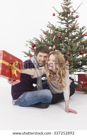 Woman reaching Christmas gift to man, smiling