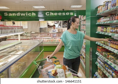 Woman Reaching For Jar On The Shelf In The Supermarket, Beijing