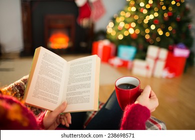 Woman reading a book and drinking coffee at christmas at home in the living room - Powered by Shutterstock