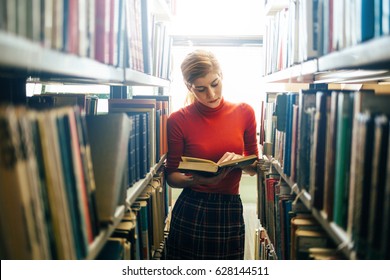 Woman reading a book in library. Portrait of college girl reading book in library - Powered by Shutterstock