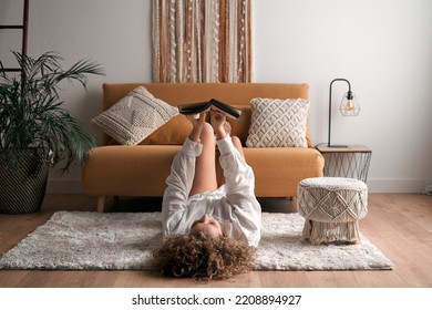 Woman reading book in living room - Shutterstock ID 2208894927