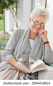 Woman Reading Book On Porch Swing