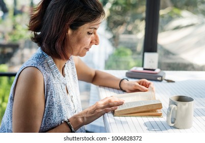 Woman reading a book in an outdoor cafe - Shutterstock ID 1006828372