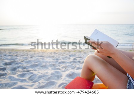 Woman reading book relaxed in deck chair. Seaview. Copy space for text.