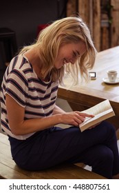 Woman Reading A Book Sitting In The Cafe