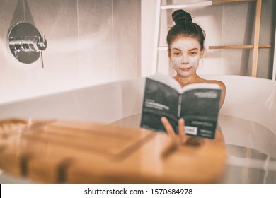 Woman Reading Book In Warm Bathtub Taking A Bath Relaxing At Home - Pamper Wellness Asian Girl Pampering Skin Care With Facial Mask Treatment.