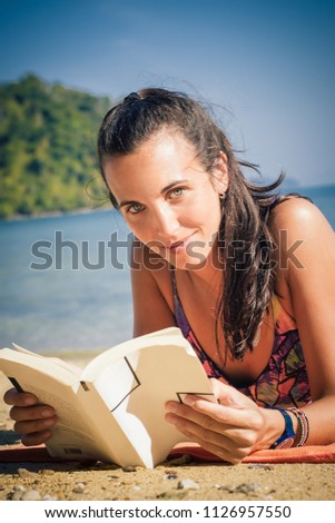 Woman reading book while enjoying the sunshine at the beach. Koh Hong Island, Thailand