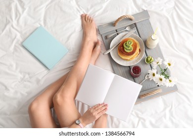 Woman reading book while having tasty breakfast in bed - Powered by Shutterstock