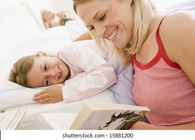 Woman Reading Book To Young Girl In Bed Smiling