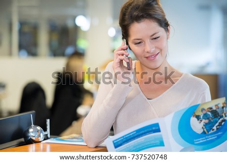 woman reading brochure and making telephone enquiry