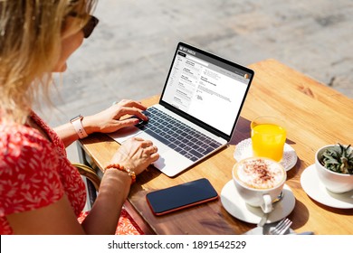 Woman reading emails on laptop at cafe. Names and all contents on screen are completely made up.